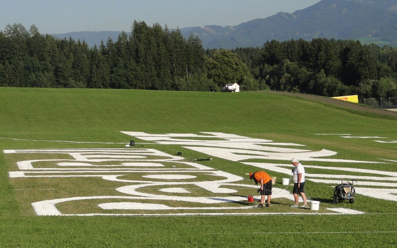Realizacja ręcznie malowanego logo Red Bull Air Race w Spielberg Austria | Mural malowany na trawie - RedBull Air Race Austria | Portfolio